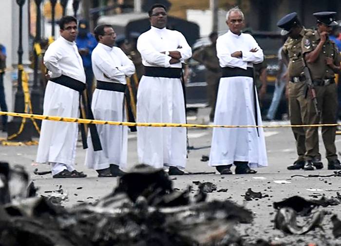 Sacerdotes miran los restos de un automóvil que explotó cuando la policía intentó desactivar una bomba, ayer, cerca del Santuario de San Antonio en Colombo, Sri Lanka. · Foto: Jewel Samad / AFP