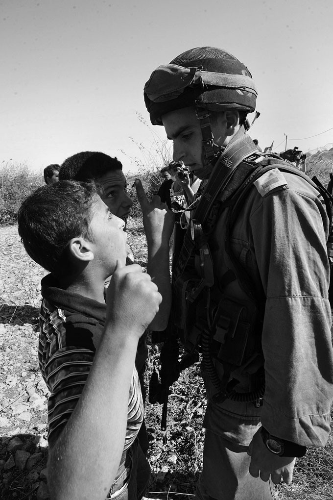 Dos jovenes palestinos se enfrentan a un soldado israeli que protege a los colonos judios en
propiedades reclamadas por los palestinos, en Beit Omar, cerca de Hebron. · Foto: Efe, Abed Al Hashlamoun