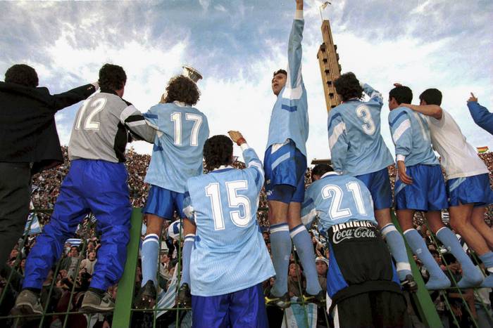 Los jugadores de la selección uruguaya y el trofeo de campeón de la Copa América,  junto al público presente en el estadio Centenario, el 23 de julio de 1995.  · Foto: David Leah, Mexsport, AFP