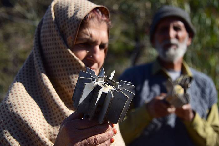 Cachemires paquistaníes con un proyectiles de mortero, que cayeron en sus casas, ayer, en la frontera que divide a Cachemira entre Pakistán y la India.

 · Foto: Sajjad Qayyum