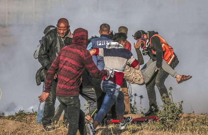 Palestinos llevan a un manifestante herido durante los enfrentamientos con las fuerzas israelíes, después de una manifestación en la cerca fronteriza con Israel, al este de la ciudad de Gaza, el 19 de abril.

 · Foto: Mahmud Hams, AFP