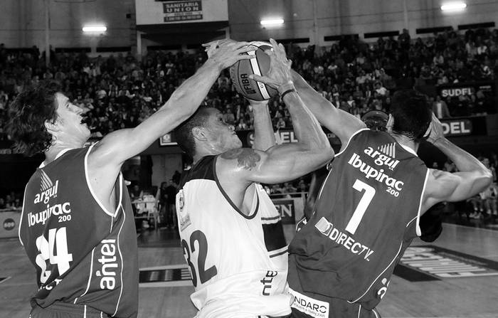 Alexis Elsener, de Malvín, Rubén Garcés, de Defensor Sporting, y Mathías Calfani, de Malvín, en el cuarto encuentro de la serie final, en el Palacio Peñarol. / foto: Pedro Rincón