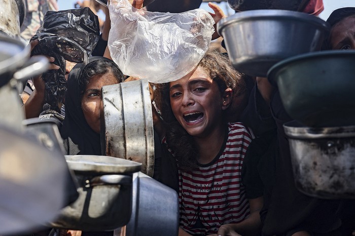 Palestinos desplazados frente a un comedor comunitario en Jan Yunis, al sur de la Franja de Gaza. · Foto: Stringer, AFP