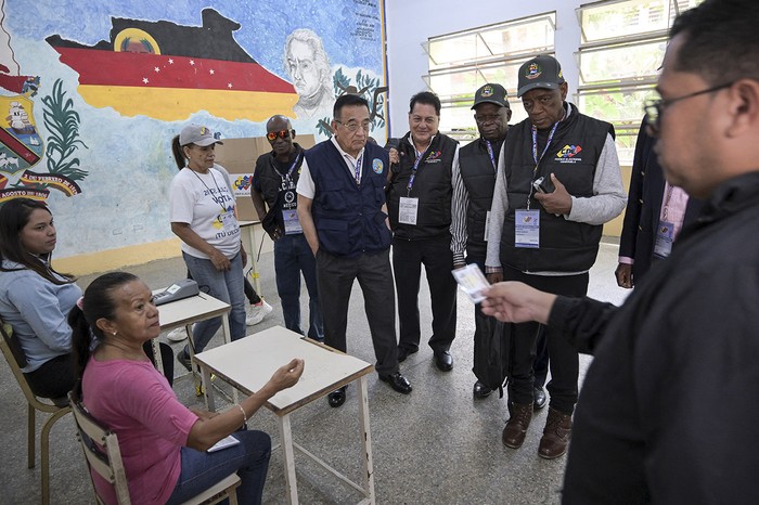 Observadores internacionales visitan uno de los centros de votación para verificar la instalación de los colegios electorales que se utilizarán en las elecciones presidenciales, en Caracas. · Foto: Yuri Cortez, AFP