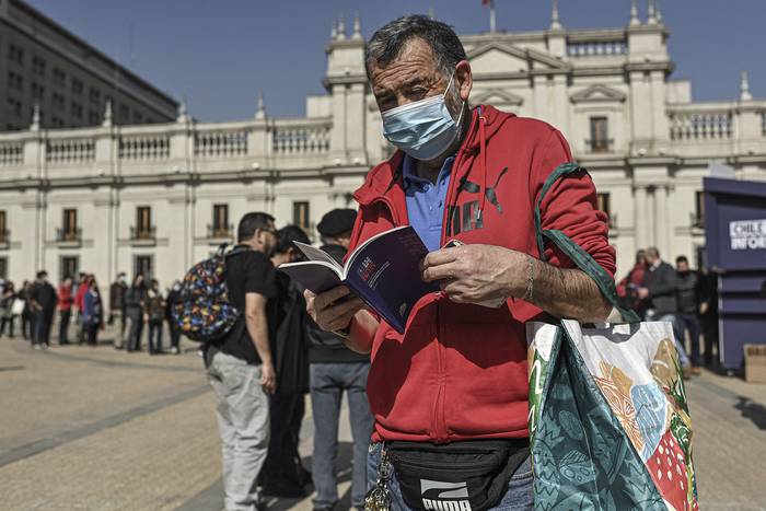 Un hombre lee una copia del borrador de la nueva constitución de Chile frente al palacio presidencial de La Moneda en Santiago, el 11 de agosto de 2022. · Foto: Martín Bernetti, AFP