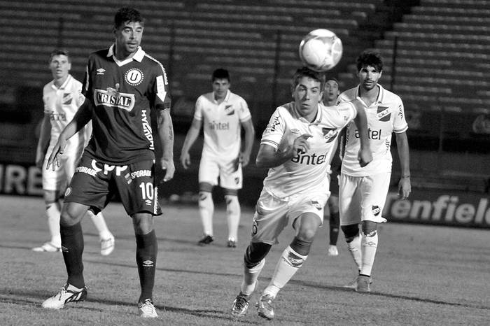 Carlos de Pena, de Nacional, y Carlos Grossmüller, de Universitario de Perú, anoche, en la final de la Copa Bandes
en el estadio Centenario. Foto: Javier Calvelo