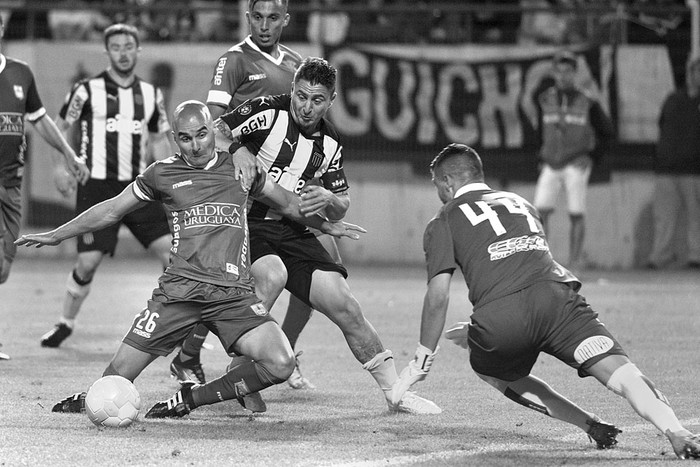 Nicolás Correa (i) y Gonzalo Reyes (d), de Defensor Sporting, y Cristian Rodríguez, de Peñarol, el domingo, en el estadio Campeón del Siglo. Foto: Andrés Cuenca