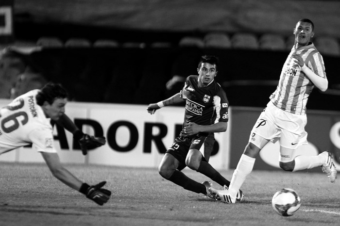 Leonardo Pais, de Defensor Sporting, entre los jugadores de Atlético Nacional, de Colombia, Franco Armani y Juan Valencia, en el estadio Centenario. / Foto: Pedro Rincón (archivo, mayo de 2014)
