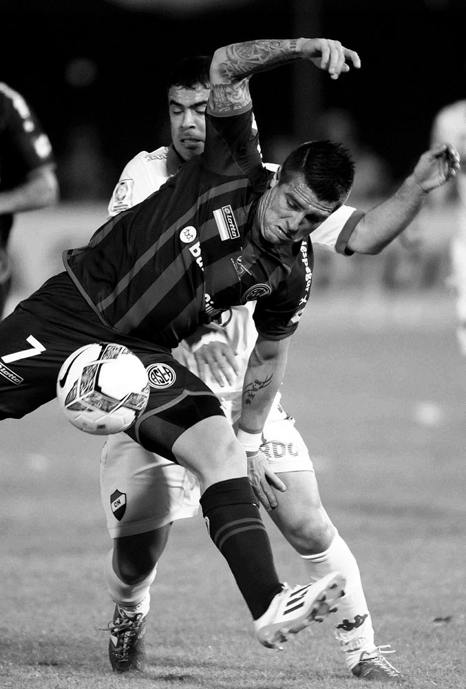 Julio Buffarini, de San Lorenzo de Argentina, y Julián Benítez, de Nacional de Paraguay, durante la primera final de la Copa Libertadores en el estadio Defensores del Chaco de Asunción (Paraguay). / Foto: Andrés Cristaldo, Efe.