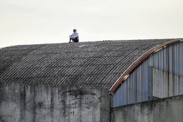 Hincha, espectador en el techo de un galpón vecino al estadio Parque Capurro, durante el partido Fénix y Peñarol,  por el torneo Apertura 2019.  · Foto: Fernando Morán