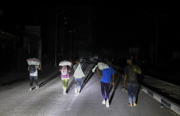 Palestinos regresan de un punto de distribución de ayuda alimentaria, en la carretera de Salaheddin, campo de refugiados de Nuseirat, en el centro de la Franja de Gaza. · Foto: Eyad Baba, AFP