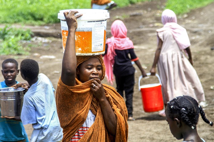 Mujeres y niños en un puesto de distribución de agua potable en Gedaref, en el este de Sudán. · Foto: Ebrahim Hamid, AFP