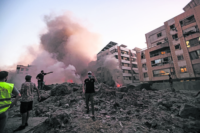 Civiles y rescatistas entre los escombros de un edificio destruido por un ataque aéreo israelí en el barrio de Haret Hreik, en los suburbios del sur de Beirut. · Foto: Ibrahim Amro, AFP