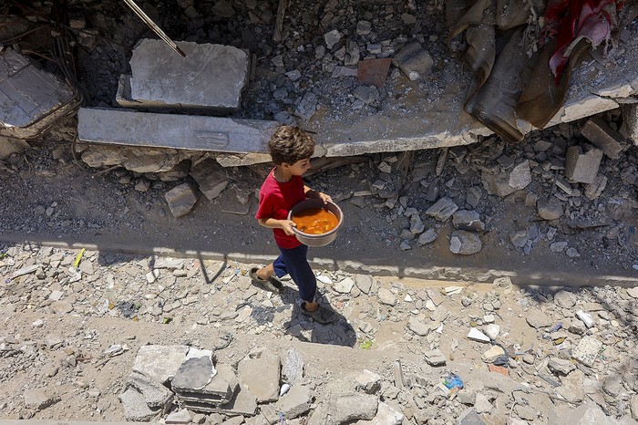 Un niño palestino luego de recibir comida en un comedor social en el barrio de Rimal, en la ciudad de Gaza. · Foto: Omar Al-Qattaa, AFP
