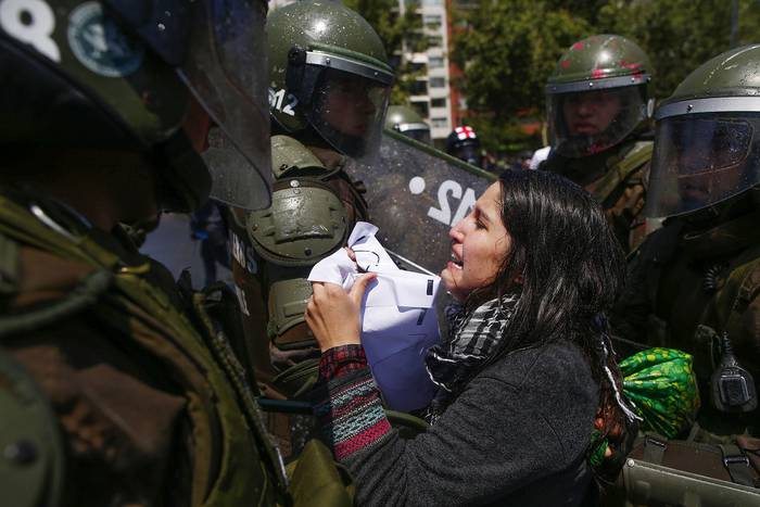 Una manifestante es detenida por la policía antidisturbios, durante las protestas, ayer, en Santiago.

 · Foto: Pablo Vera, AFP