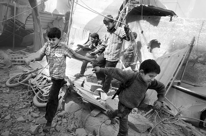 Niños sirios intentan refugiarse durante los ataques aéreos en la ciudad de Douma, Siria. Foto: Abd Doumany, AFP