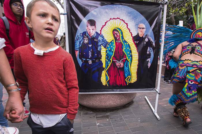 Pancarta que representa el arresto de Nuestra Señora de Guadalupe por parte de agentes fronterizos, durante una manifestación que exige que los niños separados de sus padres inmigrantes, sean restituídos a sus familias.
 · Foto: David Mcnew