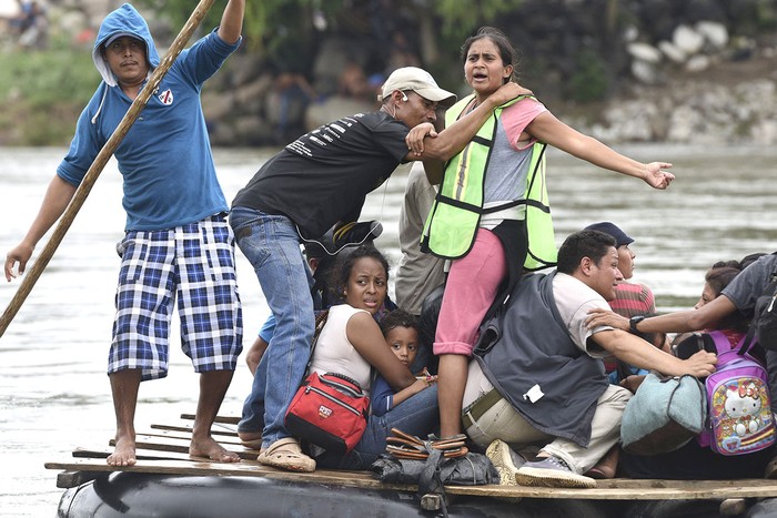 Migrantes hondureños que participan en una caravana que se dirige a los Estados Unidos, cruzan el río Suchiate, frontera natural entre Guatemala y México, en una balsa improvisada, en Ciudad Tecún, Uman, Guatemala.
 · Foto: Orlando Sierra