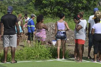 Habitantes de Guayaquil cerca del cuerpo de una mujer encontrado en el barrio donde al menos 22 personas fueron asesinadas. · Foto: Marcos Pin, AFP