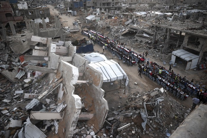 Palestinos reunidos para una comida comunitaria para romper el ayuno del Ramadán, en el campo de refugiados de Nuseirat, en el centro de la Franja de Gaza. · Foto: Eyad Baba, AFP