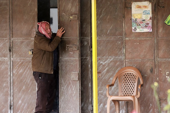 Un palestino en la puerta de su comercio en la entrada del campo de refugiados de Tulkarem, en Cisjordania, el 21 de febrero, durante una redada militar israelí en curso. · Foto: Jaafar Ashtiyeh, AFP