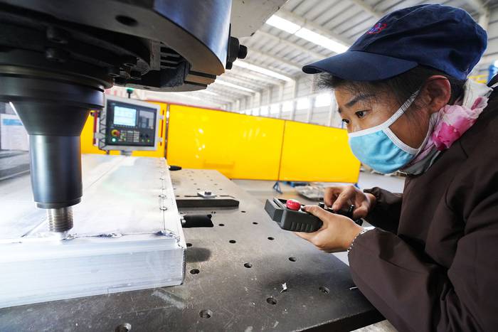 Una trabajadora suelda aluminio en una fábrica en Zouping, en la provincia china de Shandong. · Foto: AFP
