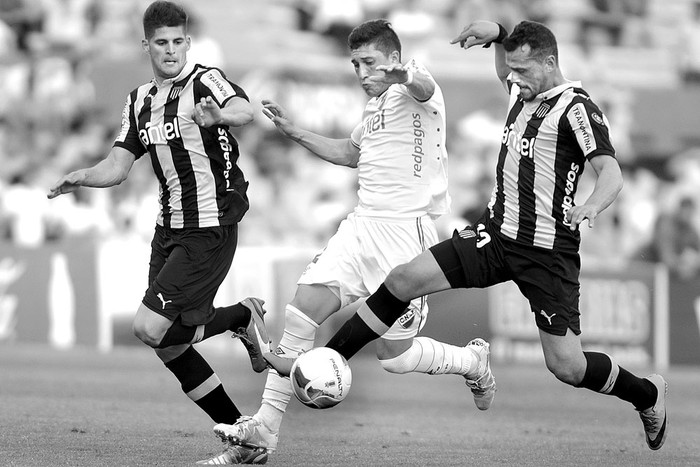 Alfonso Espino, de Nacional, entre Emilio Mac Eachen y Matías Aguirregaray, de Peñarol, en el último clásico. Foto: Iván Franco (archivo, noviembre de 2015)