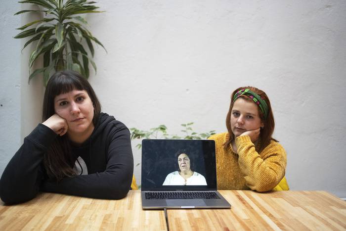 Yoseana Fernández y Fiorella Gargaglione, estudiantes de la Udelar que participan del proyecto “Sujetas- sujetadas”, en la pantalla Nibia López.
 · Foto: Mariana Greif