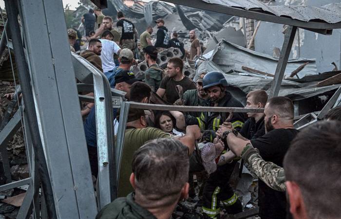 Rescatistas y voluntarios cargan a una mujer de entre los escombros después de que un misil ruso impactara en un restaurante y varias casas, el 27 de junio de 2023, en Kramatorsk, Ucrania. · Foto: Genya Savilov, AFP 