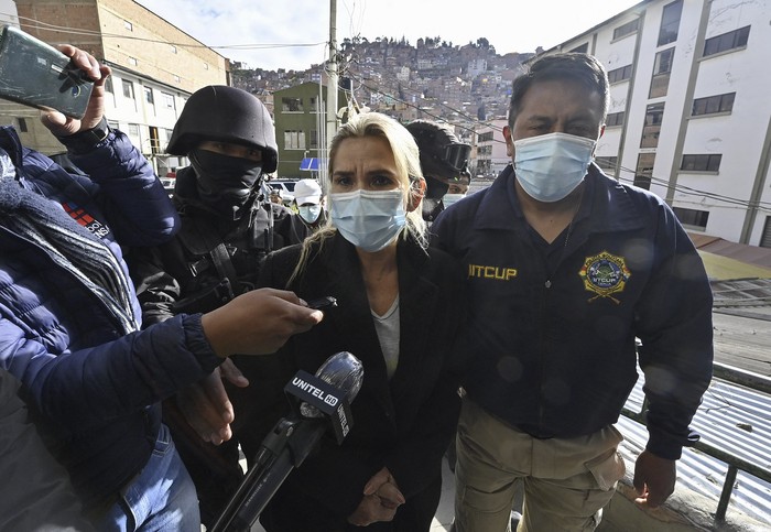 
La ex presidenta interina de Bolivia, Jeannine Añez escoltada por miembros de la Fuerza Especial contra el Crimen (FELCC) luego de ser arrestada en La Paz, el sábado 13 de marzo en La Paz.  · Foto: Aizar Raldes, AFP