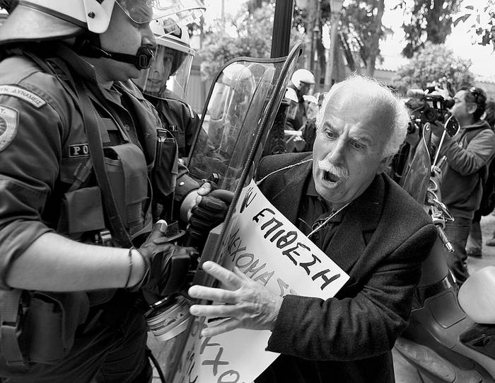 Pensionistas tratan de romper la línea de seguridad establecida por los policías antidisturbios durante una protesta convocada frente a la sede del gobierno griego, ayer, en Atenas (Grecia).  · Foto: Efe, Simela Pantzartzi