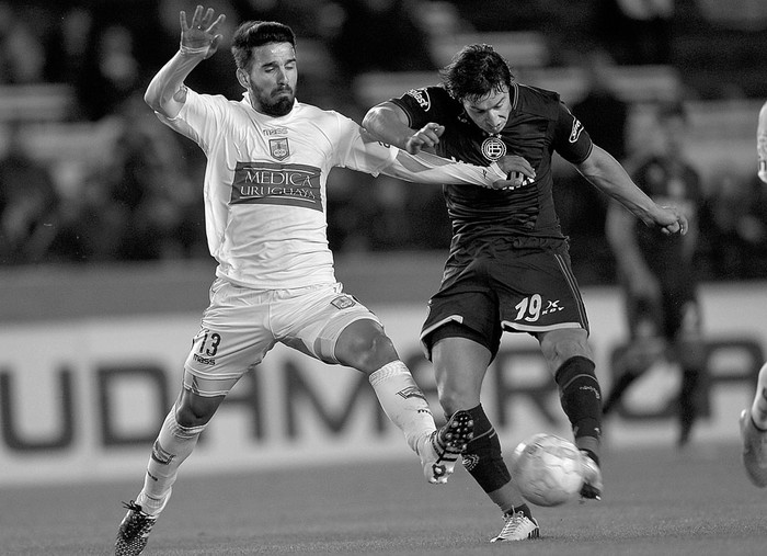 Mathías Cardaccio, de Defensor Sporting, y Nicolás Aguirre, de Lanús, durante el partido de ida por los octavos de final de la Copa Sudamericana, el jueves 24, en el estadio de Lanús, en Buenos Aires. Foto: Juan Ignacio Roncoroni, Efe