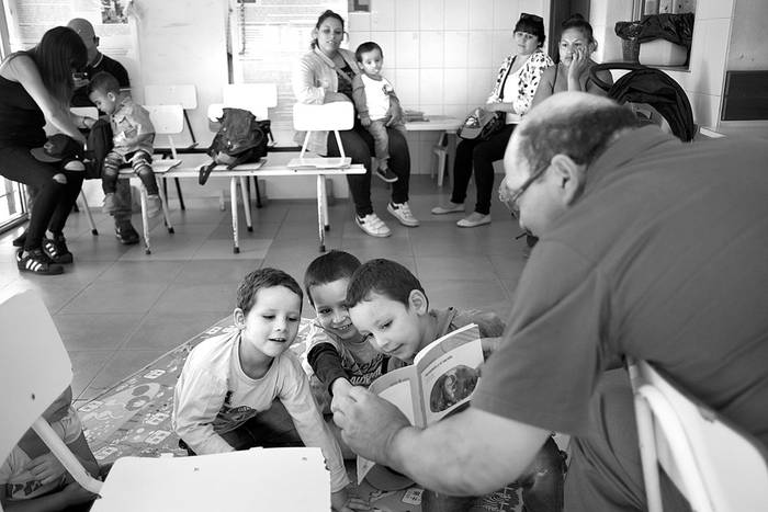 Dionisio Fleitas, voluntario que concurre cada semana, lee junto a los niños que esperan la consulta en la policlínica del Cerro. Foto: Pablo Vignali