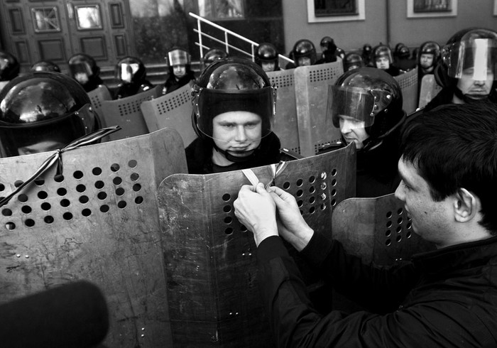 Un manifestante pro ruso colocando una cinta en el escudo de un policía antidisturbios ayer, en una concentración frente al edificio de la Fiscalía regional en Donestsk (Ucrania). Foto: Photomig, Efe, Epa