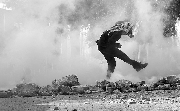 Un palestino se protege del gas lacrimógeno lanzado por soldados israelíes durante una protesta contra el asentamiento judío de Qadomem, cerca de la ciudad cisjordana de Naplusa, el viernes. · Foto: Alaa Badarneh, Efe