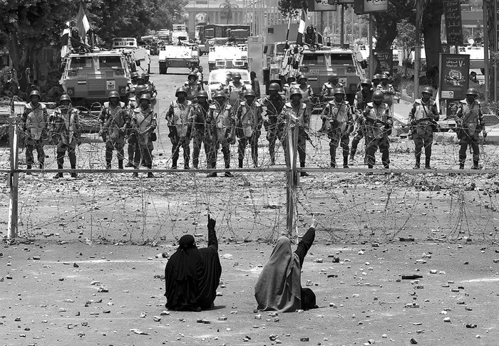 Miembros de los Hermanos Musulmanes permanecen sentados ante las fuerzas de seguridad, durante enfrentamientos, ayer en El Cairo, Egipto. · Foto:  Khaled Elfiqi, Efe