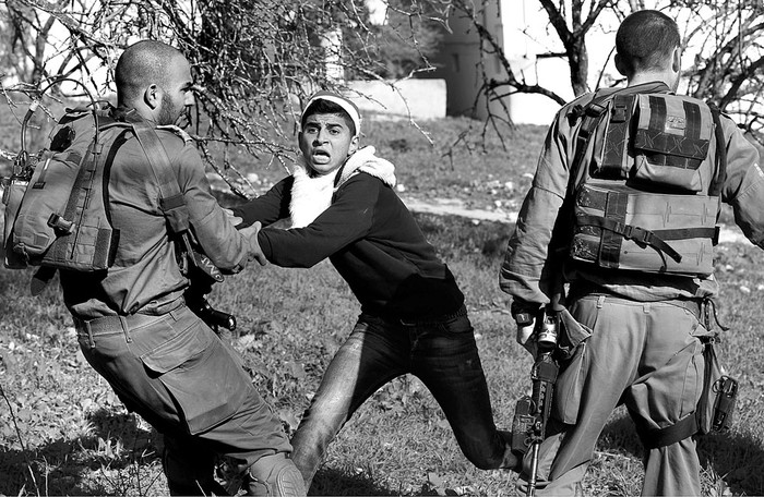 Un manifestante palestino vestido de Papá Noel es detenido por un soldado israelí, ayer, durante una protesta en el punto de control de Howara, cerca de Nablus, en Palestina. Foto: Alaa Badarneh, Efe