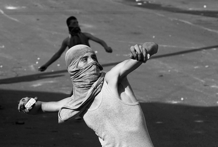 Palestinos lanzan piedras a las fuerzas de seguridad israelíes, ayer, durante los enfrentamientos en la ciudad cisjordana de Hebrón. Foto: Hazem Bader, Afp