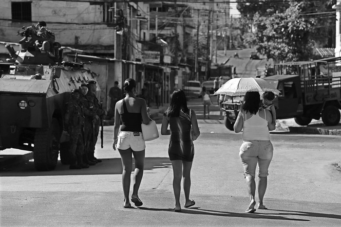 Mujeres caminan junto a un tanque del Ejército brasileño que ocupó ayer la favela de Muquiço, en Río de Janeiro,
para garantizar la seguridad durante actos de campaña previos a las elecciones municipales del domingo.  · Foto: Efe, Marcelo Sayao