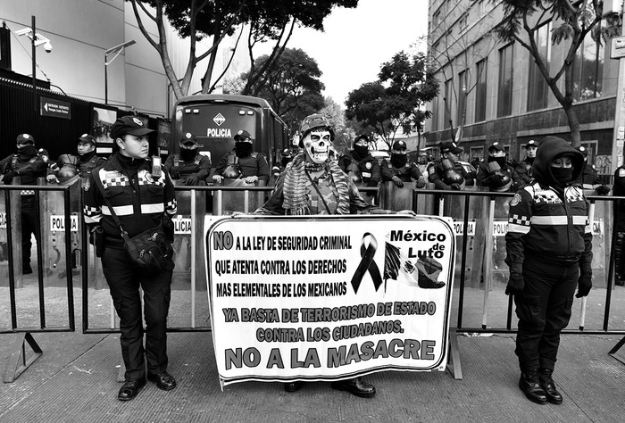 Manifestante y policías durante el tratamiento de la Ley de Seguridad Interna por la Cámara de Senadores de México. / Foto: Yuri Cortez, Afp