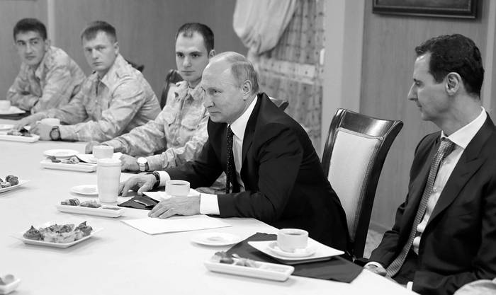 Vladimir Putin junto a Bashar al Assad (d), ayer, en un encuentro con militares rusos en la base aérea rusa de Hmeimim, Siria. Foto: Mikhail Klimentyev, AFP