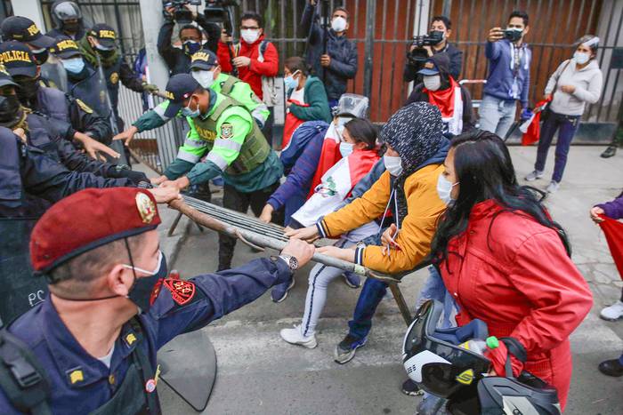 Un grupo de personas que se hacen llamar Combatientes del Pueblo, cercanos al Fujimorismo, intentan romper la barrera policial con la intención de ver el cuerpo de Abimael Guzmán, el lunes, fuera de la morgue del Callao, en Lima, Perú. · Foto: EFE, s/d autor