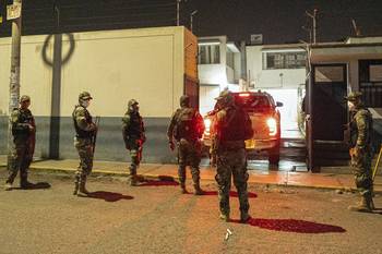 Agentes de policía custodian la entrada de la morgue mientras llegan camionetas con los cuerpos de 13 trabajadores hallados muertos en una mina de oro en Trujillo, Perú, el 5 de mayo. · Foto: AFP