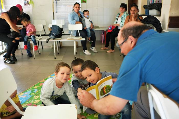 Dionisio Fleitas, voluntario que concurre cada semana, lee junto a los niños que esperan la consulta. Foto: Pablo Vignali


