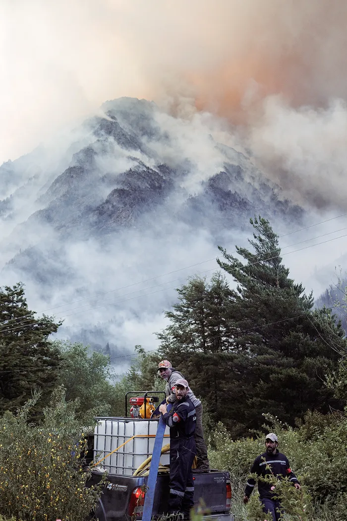 Integrantes de la Brigada Patagónica cargan agua para combatir un incendio en el cerro Pirque. · Foto: Denali Degraf