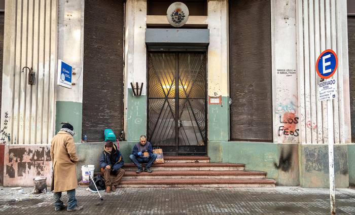 Personas en situacion de calle esperan para ingresar en el refugio nocturno de Paysandu y Rio Branco, en el centro de Montevideo (archivo, julio de 2020). · Foto: Mauricio Zina, adhocfotos