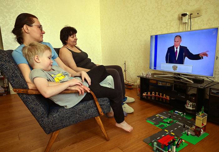 Una familia mira el discurso anual sobre el estado de la nación del presidente ruso Vladimir Putin, en Moscú (21.02.2023). · Foto: Yuri Kadobnov, AFP