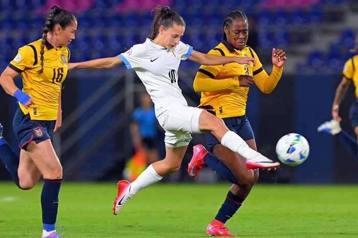 La delantera uruguaya Belén Aquino, y las ecuatorianas Ligia Moreira y Mayerli Rodríguez, el 11 de julio, en el estadio IDV en Quito. · Foto: Rodrigo Buendía, AFP