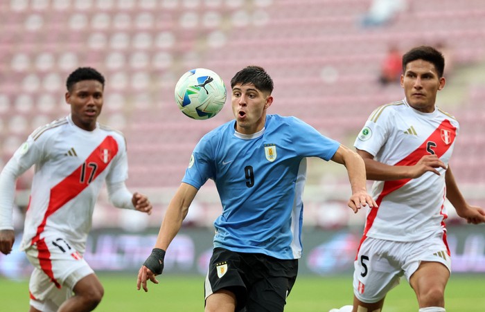 Renzo Machado, de Uruguay, entre los peruanos Jonathan García y Alejandro Posito, el 29 de enero, en el Estadio Metropolitano de Lara, Venezuela. · Foto: Edilzon Gamez, AFP