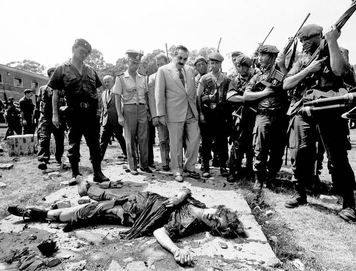 El presidente Raúl Alfonsín observa a uno de los guerrilleros muertos luego del asalto el 24 de enero de 1989. Foto: s/d de autor